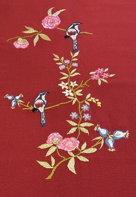 Branche fleurie aux deux oiseaux brodée sur un chemin de table