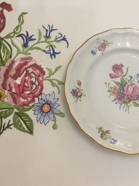 Nappe blanche brodée aux motifs floraux assorties aux assiettes.