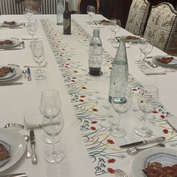 Chemin de table brodé sur une nappe blanche, représantant des fleurs des champs coquelicots, herbes folles et épis de blé. Cette élégante nappe est un modèle unique réalisé sur mesure.