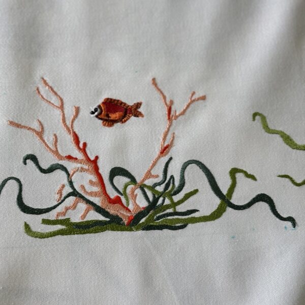 Zoom sur l'art de la précision : un poisson et sa structure de corail en broderie informatique..