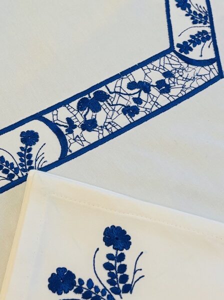 Gros plan sur les délicats motifs floraux brodés  et les serviettes brodées assorties.